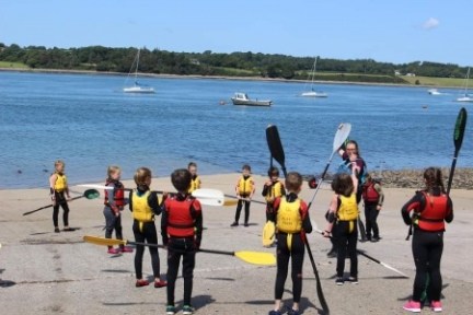 a group of people walking in front of a body of water