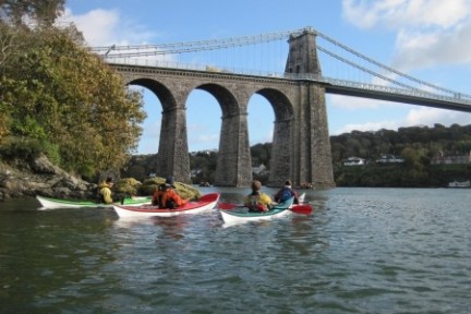 a group of people crossing a bridge over a body of water
