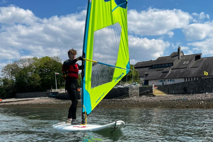 a youth windsurfing on a large body of water